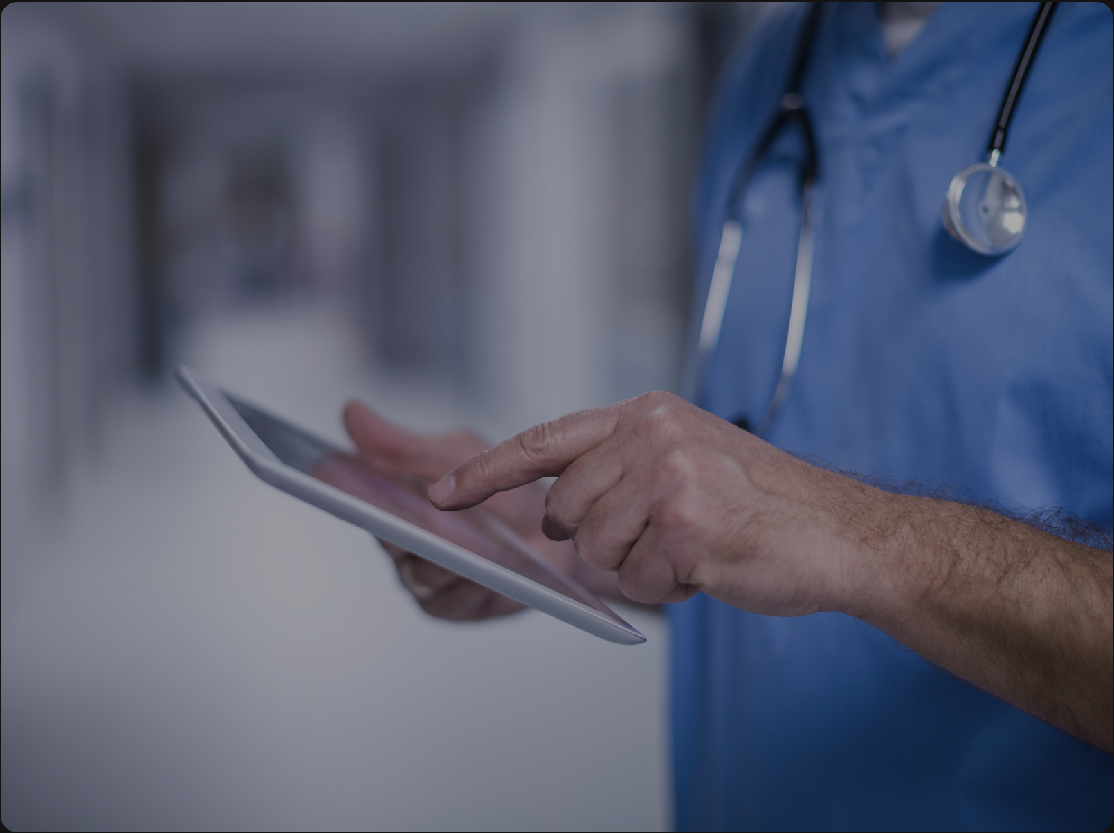 Doctor in scrubs using a digital tablet in hospital hallway, enhancing healthcare technology and patient care.